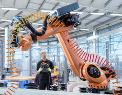 Junger Mann bedient einen Industrieroboter Junger Mann bedient einen Industrieroboter
